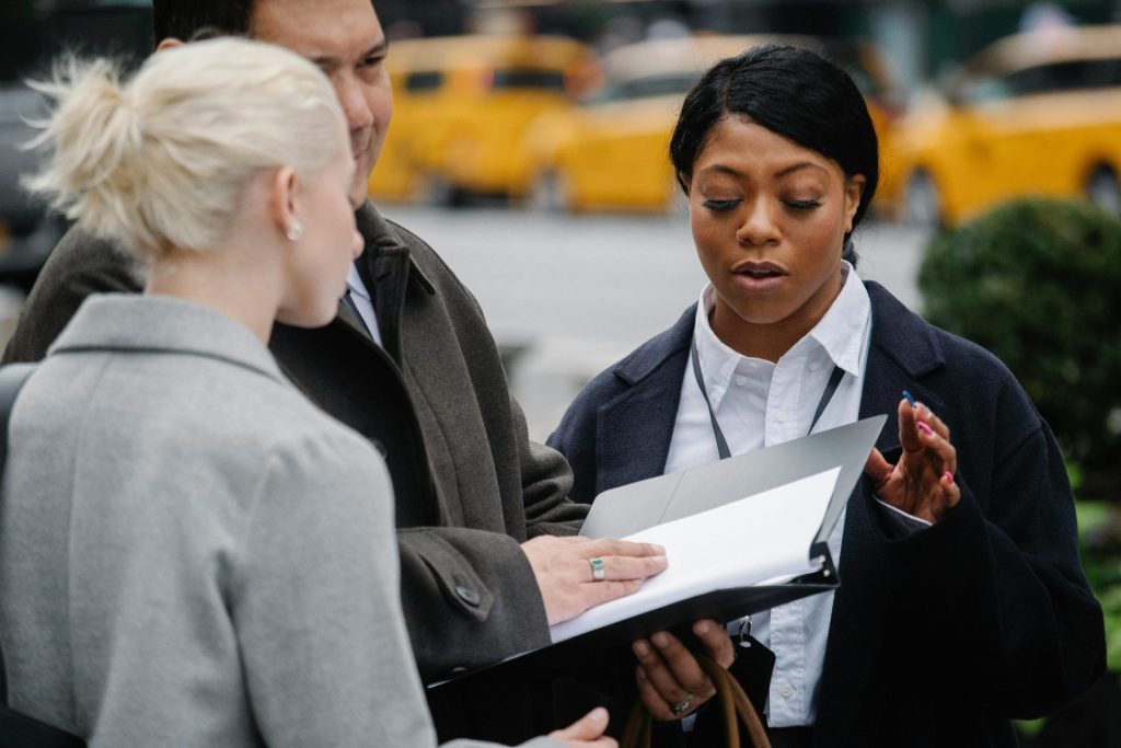 Three people discussing paperwork outdoors